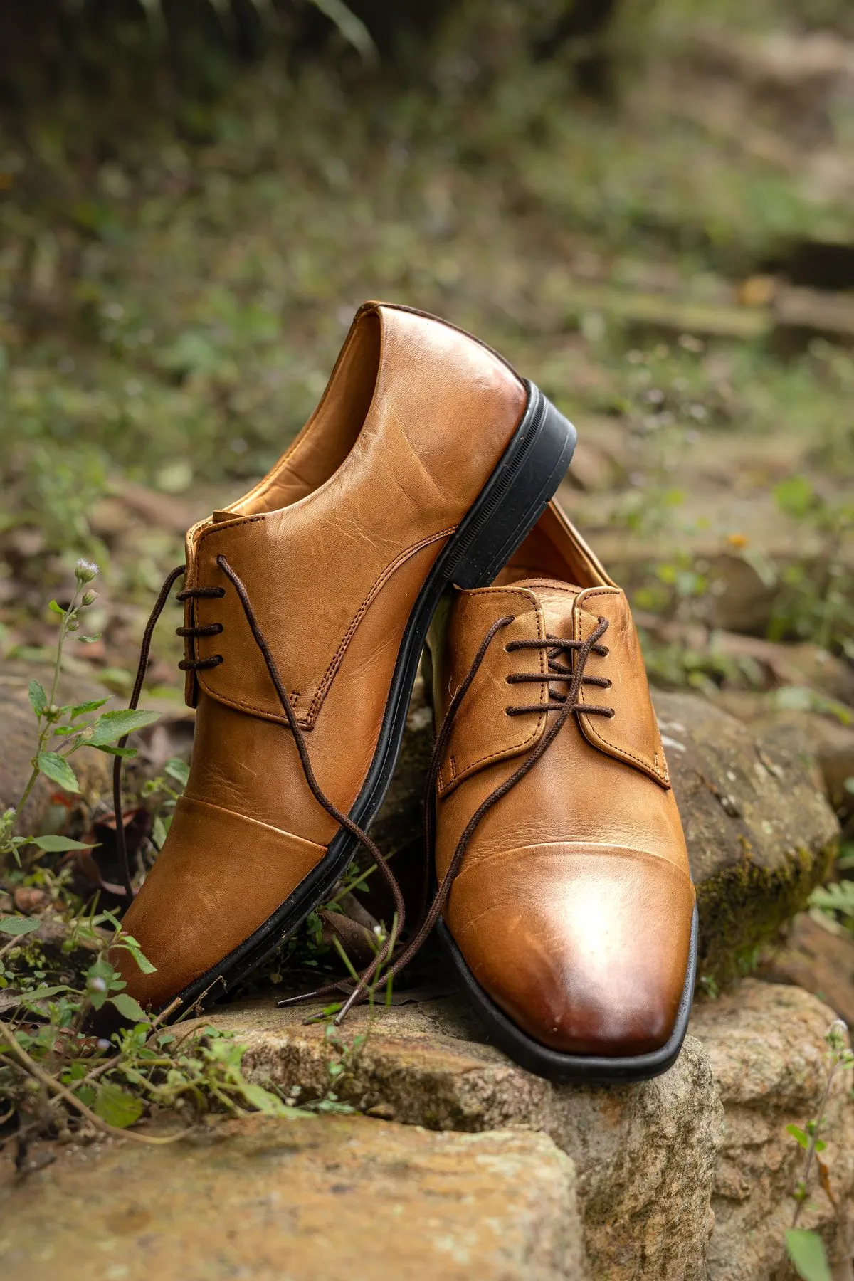 Zapatos de vestir de cuero color miel con cordones, apoyados sobre piedra