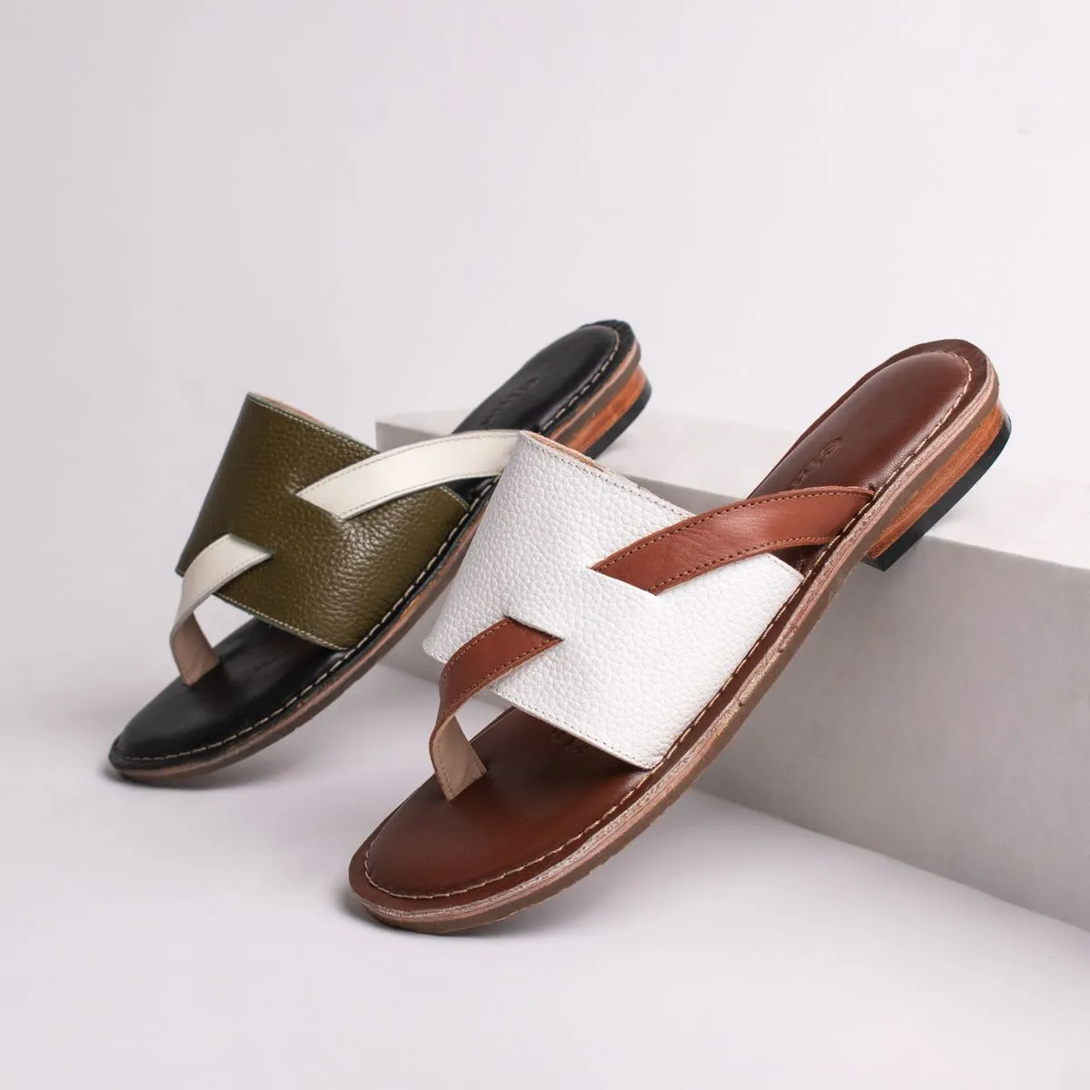 Tres sandalias de cuero en verde, blanco y marrón sobre bloques claros