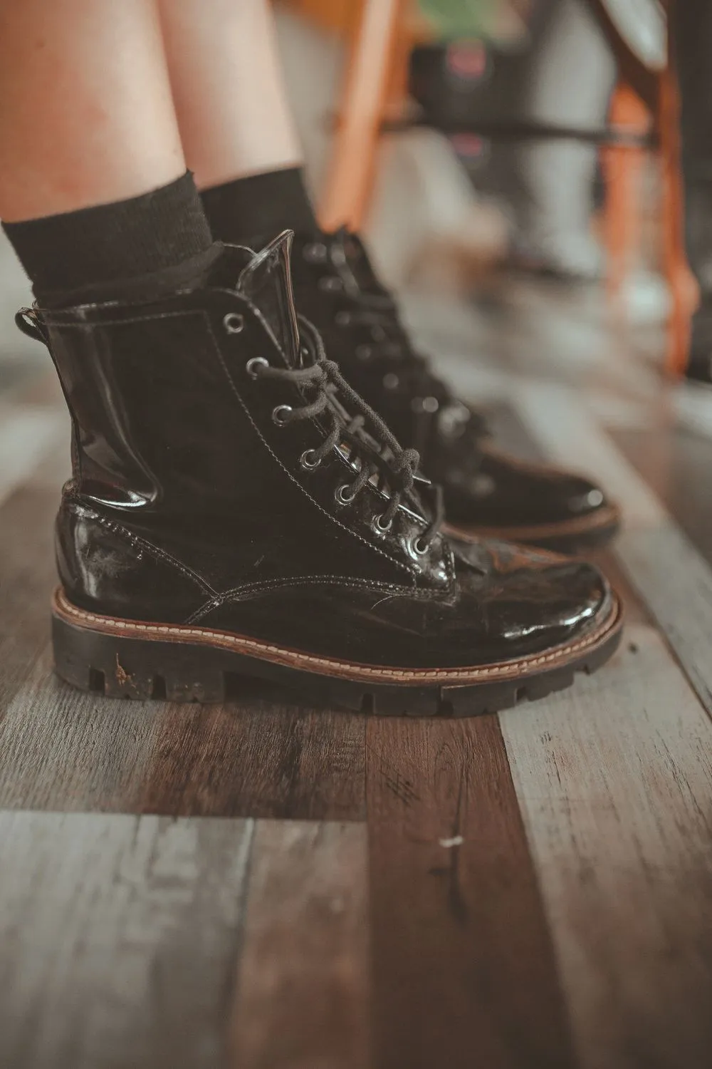 Botines de charol negro con cordones, puestos, sobre un piso de madera